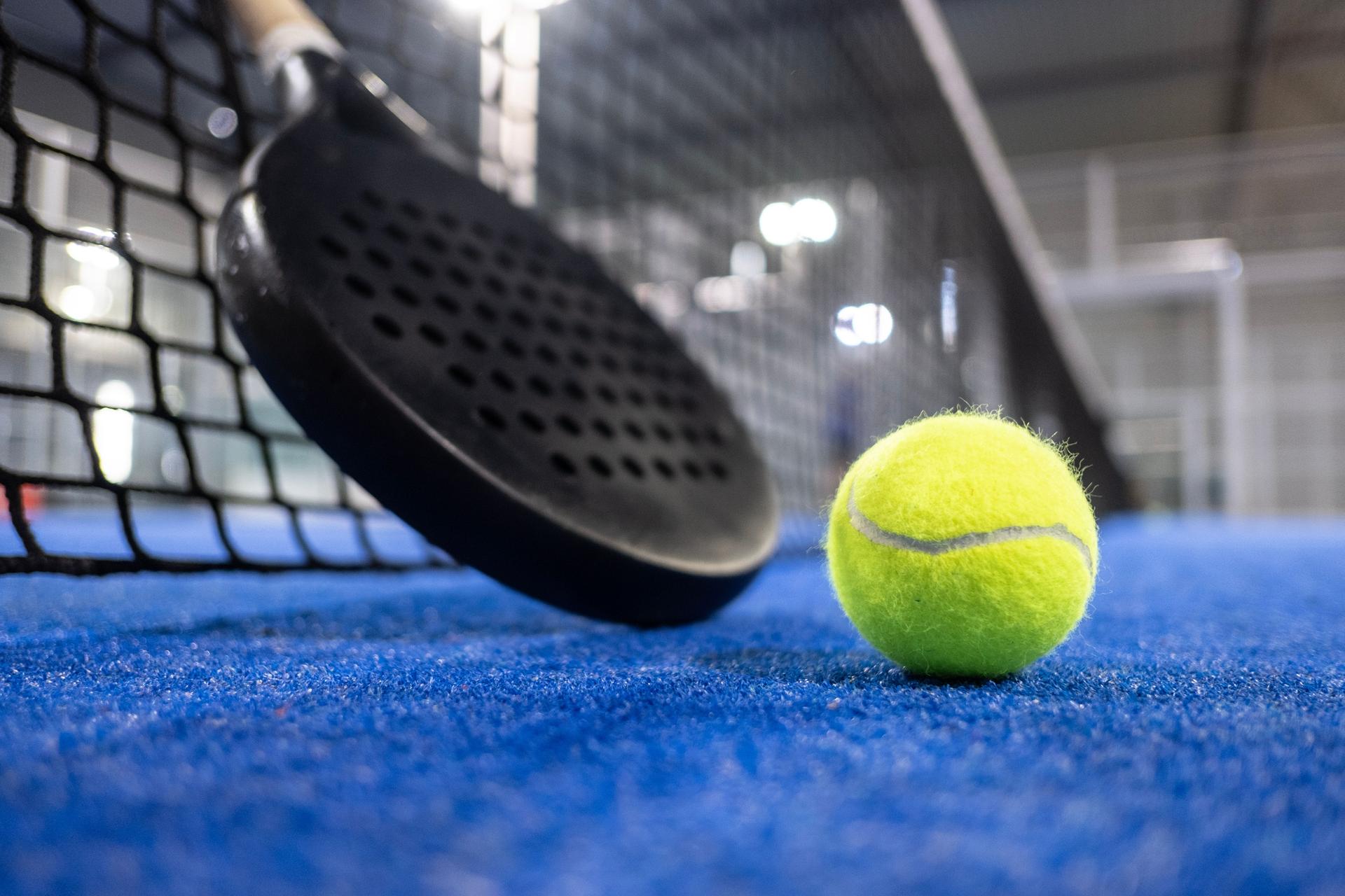 Paddle tennis racket and balls on blue turf