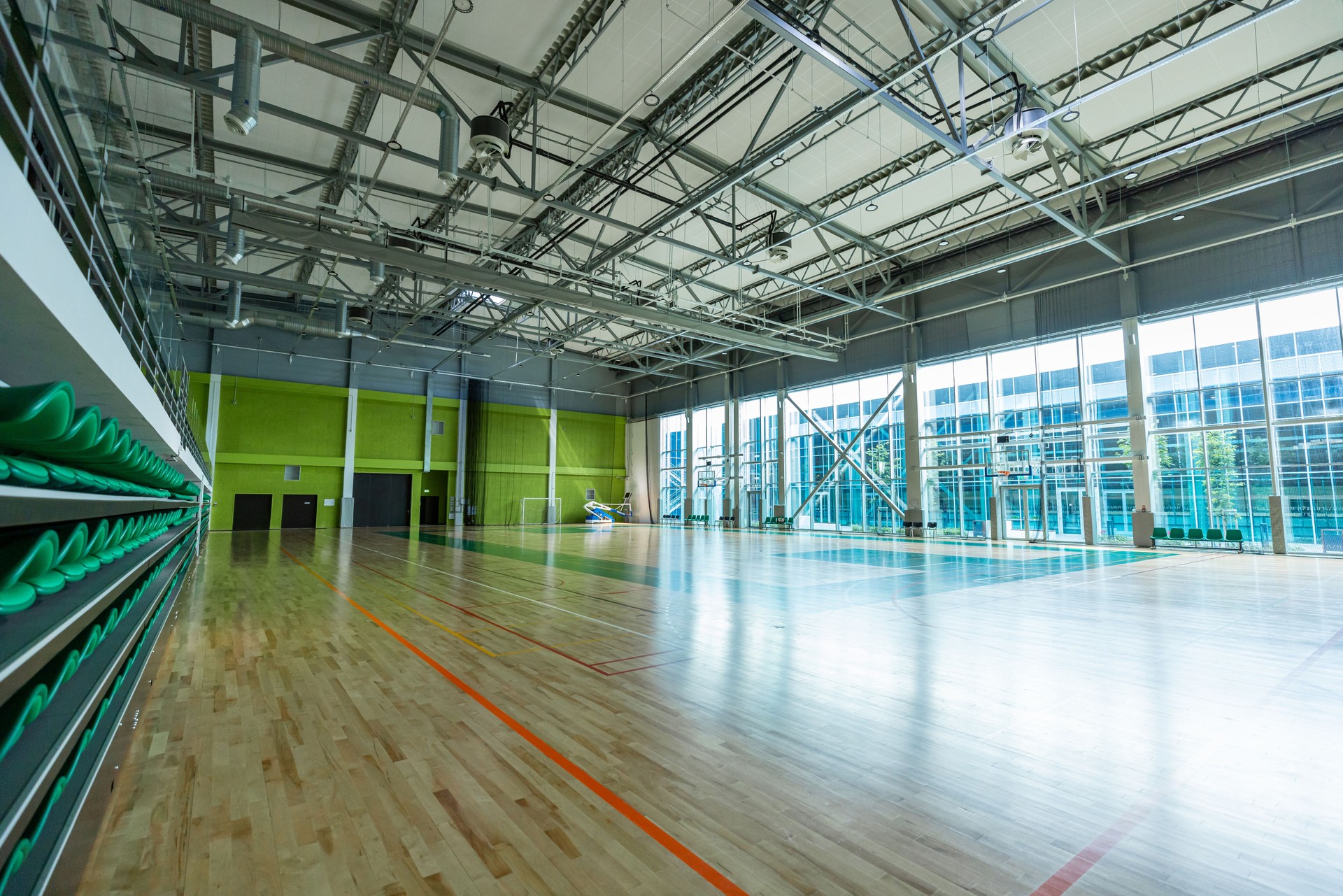 Spacious Modern Indoor Sports Arena with Vibrant Green Spectator Seats and Natural Lighting